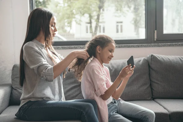 Mutter flechtet Haare ihrer Tochter — Stockfoto