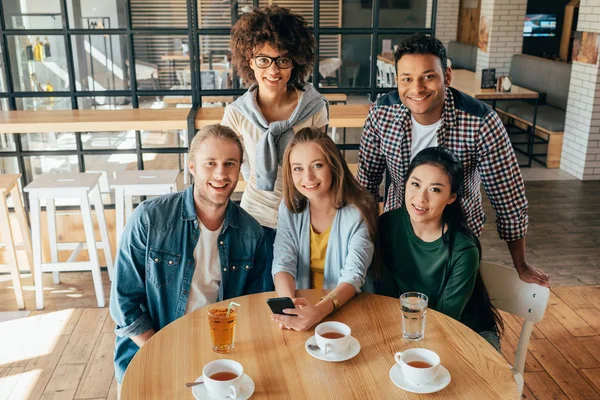 Amigos multiétnicos con bebidas en la cafetería - foto de stock