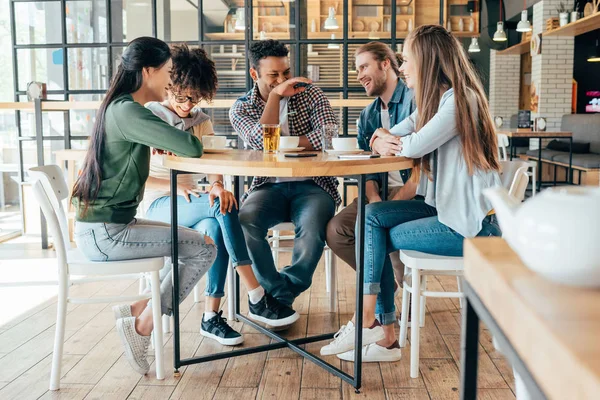 Amigos multiétnicos con bebidas en la cafetería - foto de stock