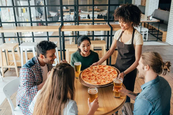 Официантка приносит пиццу для клиентов — стоковое фото