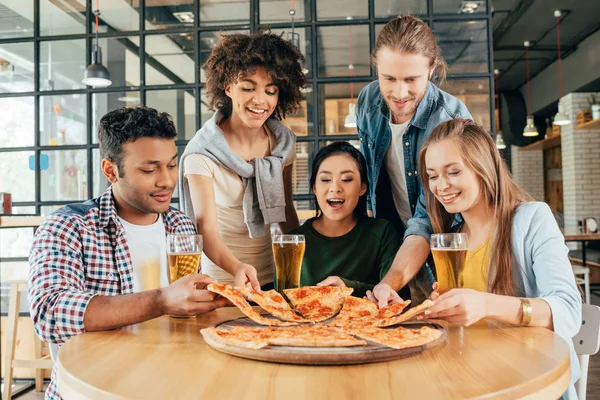 Amigos teniendo pizza en la cafetería - foto de stock