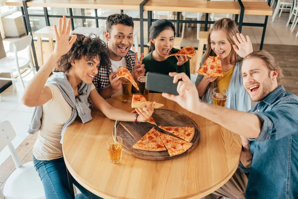 Amigos tomando selfie con pizza en la cafetería - foto de stock