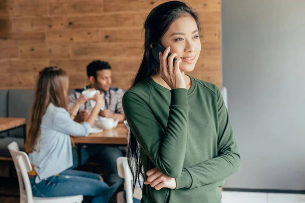 Mujer asiática hablando en teléfono inteligente en la cafetería - foto de stock