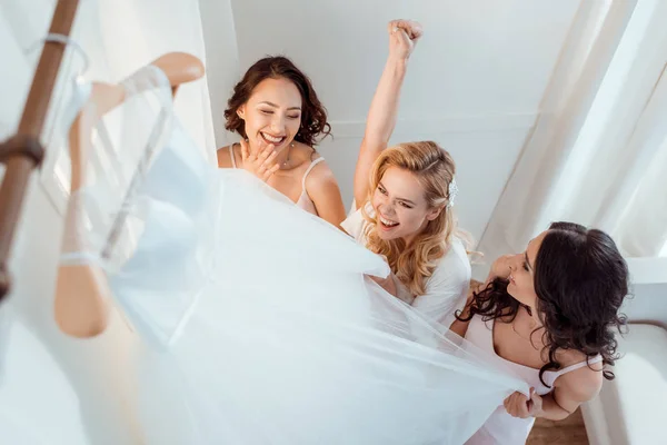 Novia con damas de honor tocando vestido de novia - foto de stock