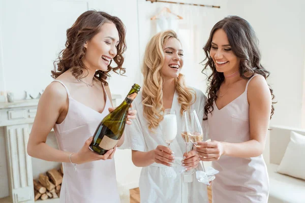 Braut mit Brautjungfern, die Champagner in Gläser gießen — Stockfoto