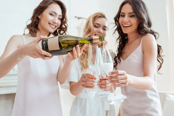 Braut mit Brautjungfern, die Champagner in Gläser gießen — Stockfoto