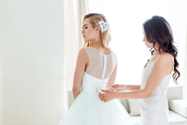 Bridesmaid dressing up bride — Stock Photo