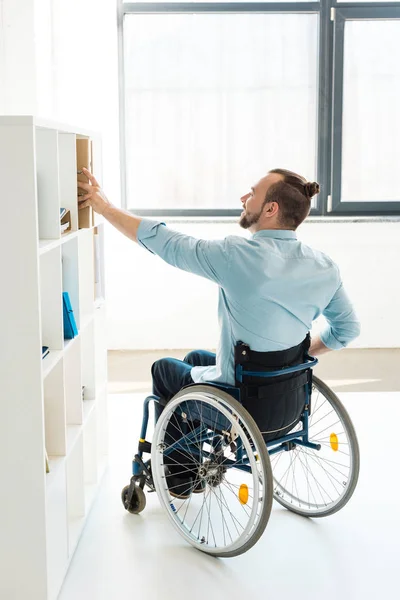 Disabled businessman reaching to shelf — Stock Photo