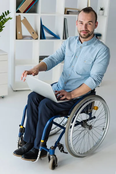 Hombre de negocios en silla de ruedas con portátil - foto de stock