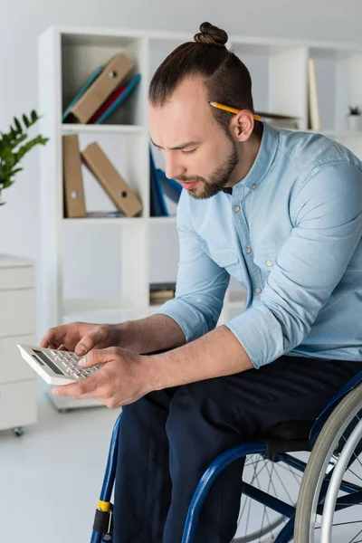 Hombre de negocios en silla de ruedas usando la calculadora - foto de stock