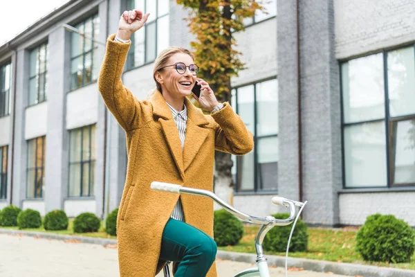 Mujer hablando en el teléfono inteligente mientras monta bicicleta - foto de stock