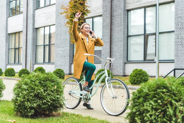 Mujer hablando en el teléfono inteligente mientras monta bicicleta - foto de stock