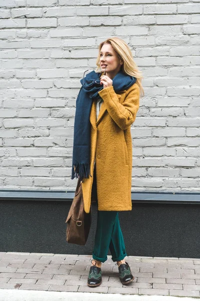 Pensive woman in yellow coat — Stock Photo