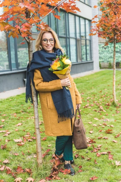 Stylish woman with flowers in autumn park — Stock Photo
