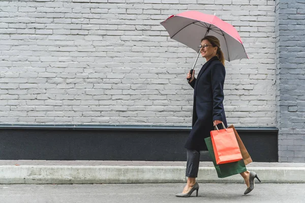 Femme avec parapluie et sacs à provisions — Photo de stock