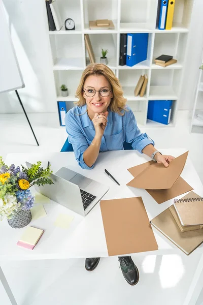 Empresaria que trabaja con documentos y laptop - foto de stock