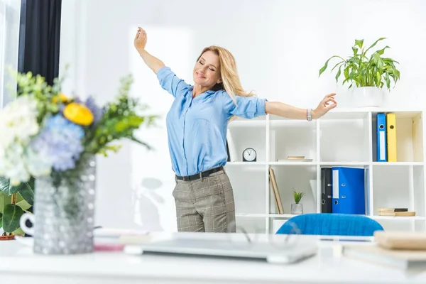 Businesswoman stretching in modern office — Stock Photo