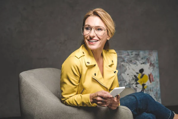 Femme souriante utilisant un smartphone — Photo de stock