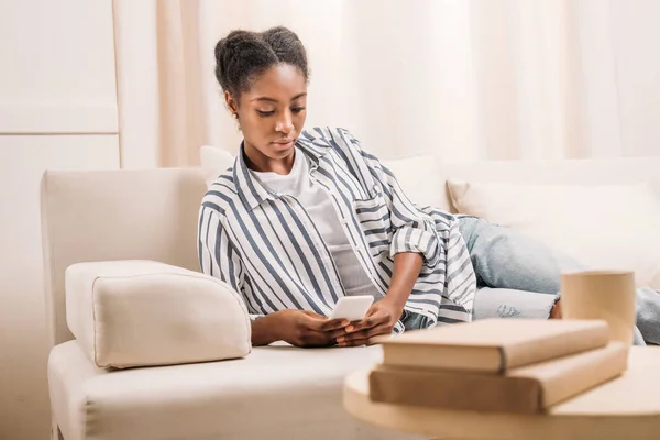 Femme sur le canapé en utilisant un smartphone — Photo de stock