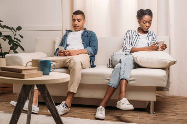 Pareja sentada con smartphones - foto de stock