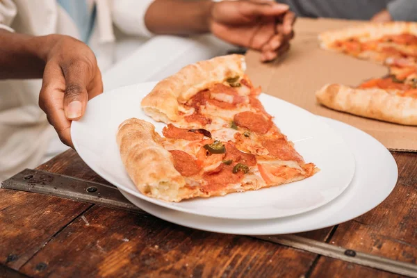 Female hands holding plate with pizza — Stock Photo