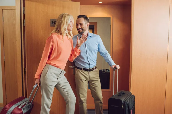 Счастливая зрелая пара с чемоданами смеются в номере отеля — стоковое фото