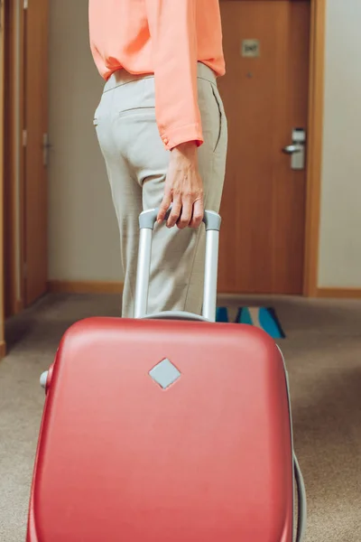 Schnittwunden an Frau, die mit Koffer durch Hotelflur läuft — Stockfoto