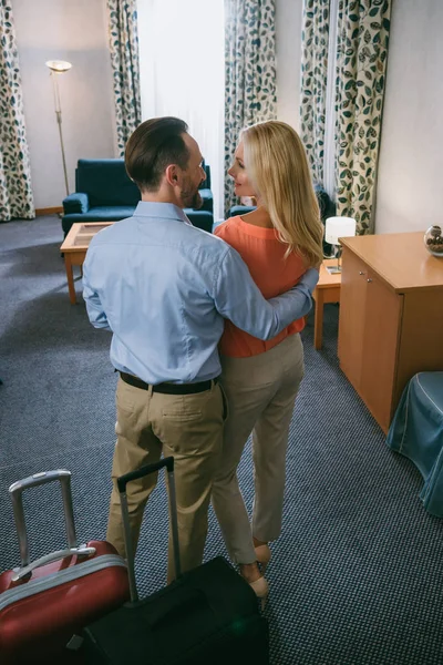 Rückansicht eines glücklichen, reifen Paares, das mit Koffern im Hotelzimmer steht — Stockfoto