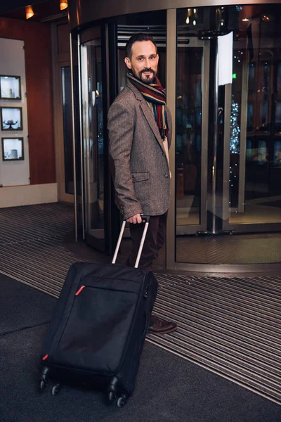 Handsome middle aged man with suitcase entering modern hotel — Stock Photo