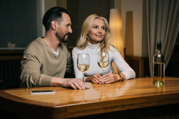 Happy mature couple drinking wine and looking away in hotel restaurant — Stock Photo