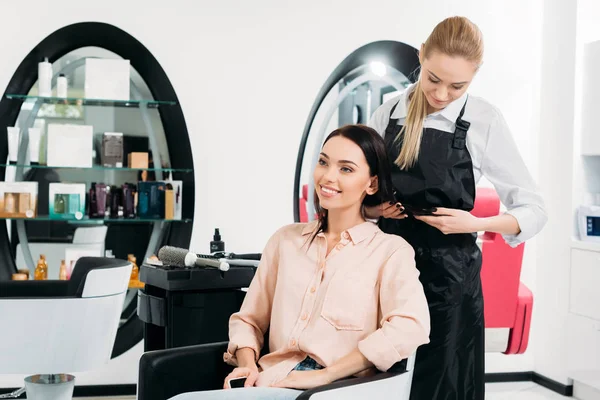 Hairdresser looking at new hairstyle of customer — Stock Photo