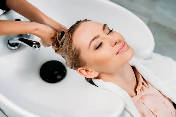 Image recadrée de coiffeur laver les cheveux pour le client avec shampooing — Photo de stock