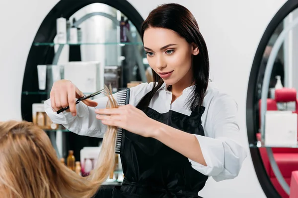 Cropped image of attractive hairdresser trimming ends of hair — Stock Photo