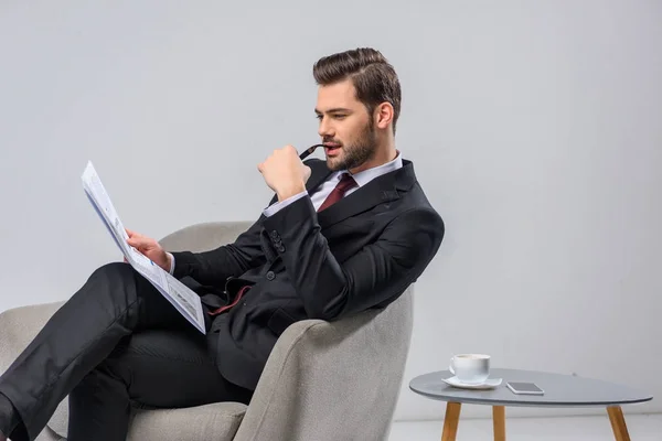 Hombre de negocios mordiendo gafas y leyendo el periódico - foto de stock