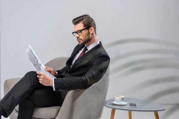 Homme d'affaires assis dans le fauteuil et lire le journal — Photo de stock