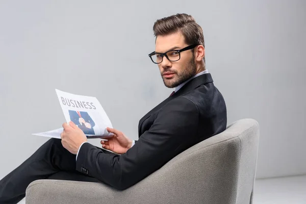 Businessman sitting in armchair and holding newspaper — Stock Photo