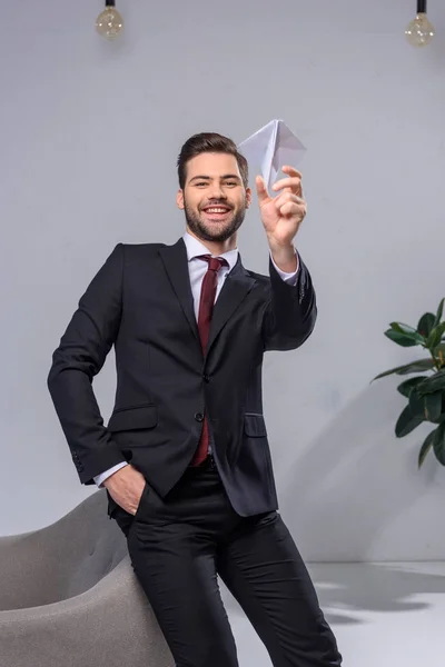 Счастливый бизнесмен бросает бумажный самолет в офис — стоковое фото