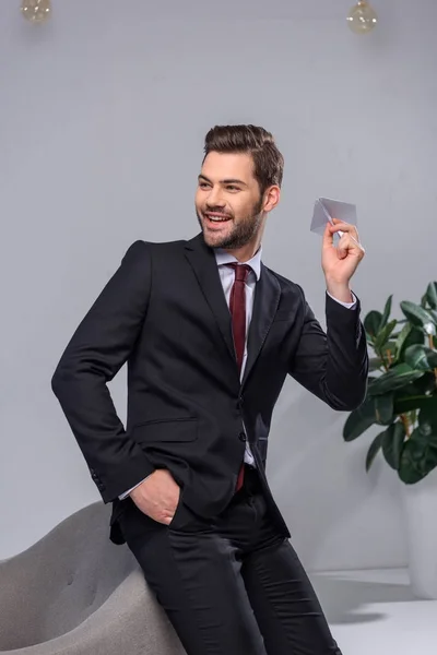 Sonriente hombre de negocios lanzando avión de papel en la oficina - foto de stock