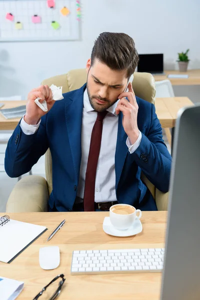 Aggressive businessman talking by smartphone and crumpling note — Stock Photo