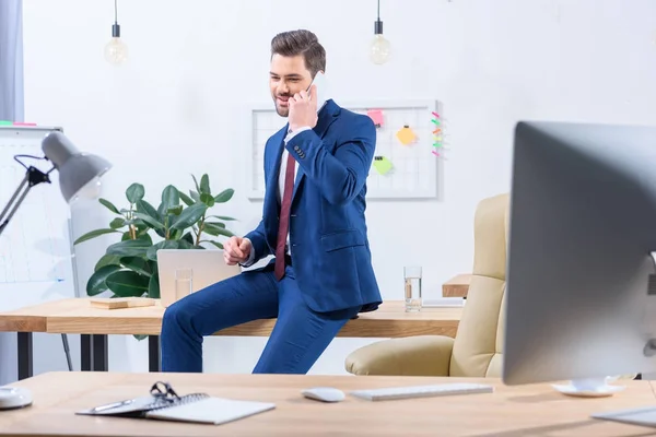 Glücklicher Geschäftsmann, der im Büro per Smartphone spricht — Stockfoto