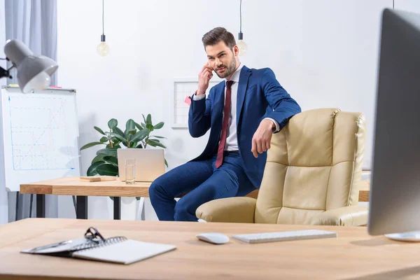Homem de negócios bonito falando por smartphone no escritório — Fotografia de Stock