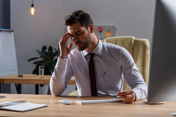 Homem de negócios doente com dor de cabeça enquanto trabalhava à noite no escritório — Fotografia de Stock