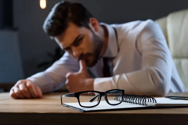 Stanco uomo d'affari pensoso appoggiato sul tavolo con gli occhiali in primo piano — Foto stock