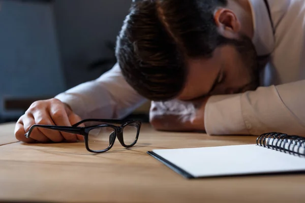 Abgeschnittenes Bild eines müden Geschäftsmannes, der am Arbeitstisch schläft — Stockfoto