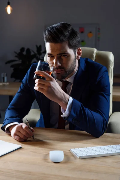 Businessman drinking whiskey and looking at camera — Stock Photo