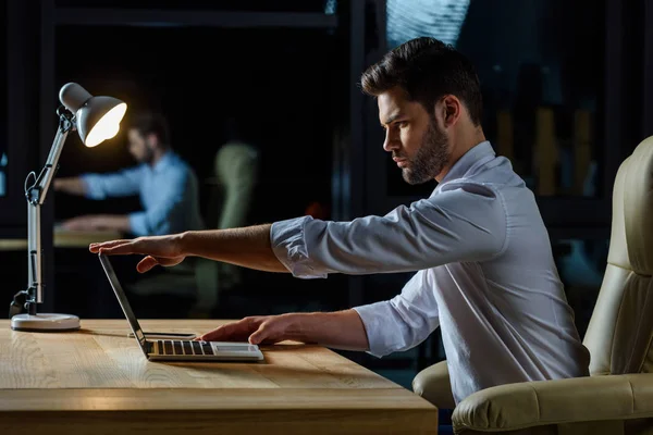 Seitenansicht eines Geschäftsmannes, der Laptop am Tisch öffnet — Stockfoto