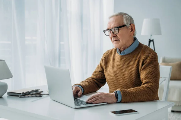 Uomo anziano fiducioso che lavora sul computer portatile — Foto stock