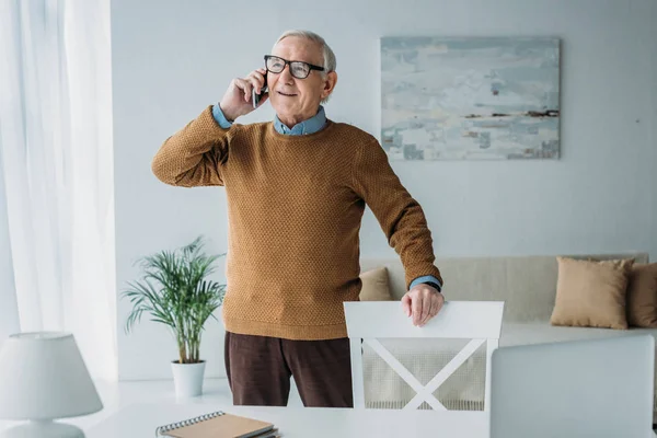 Aîné souriant homme travaillant dans le bureau et passer un appel téléphonique — Photo de stock