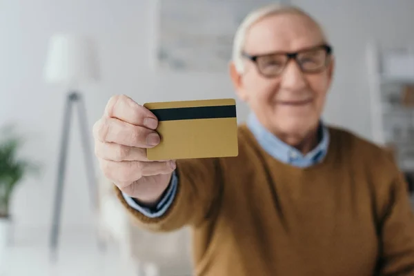 Hombre sonriente mayor sosteniendo tarjeta de crédito - foto de stock