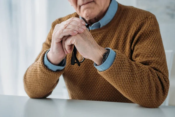 Hombre serio y reflexivo sentado junto al escritorio en la sala de luz - foto de stock